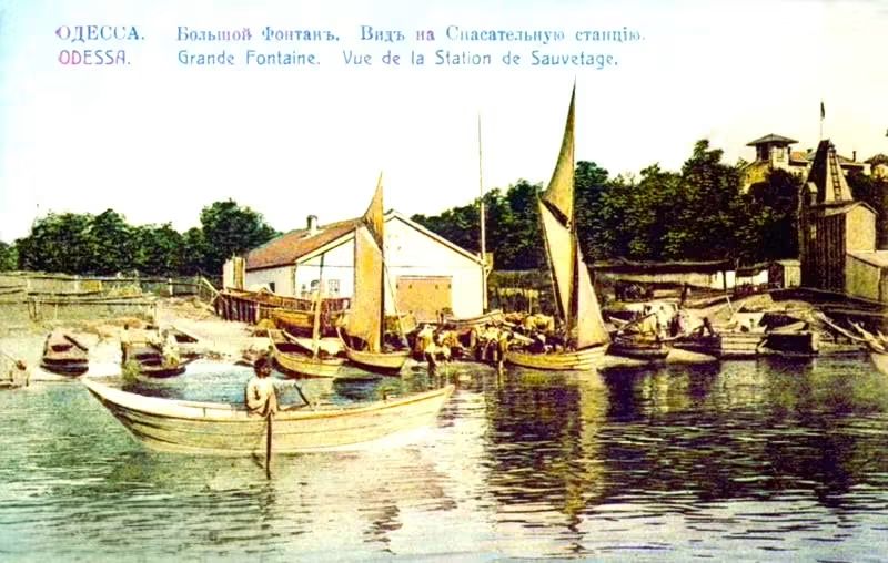 Човни й вітрильники біля берега, на березі білий будинок і дерева