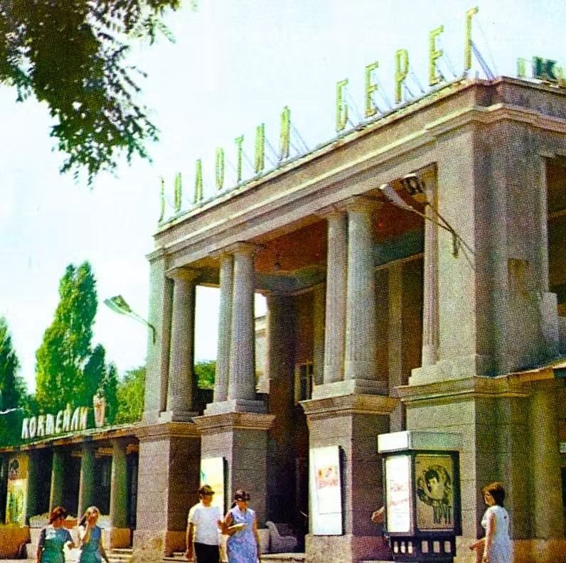 Колонада кінотеатру з великими літерами «Золотий берег» на даху, перед входом перехожі